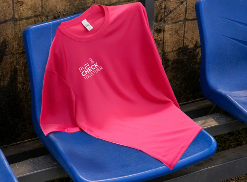 T-shirt rose « Run Check Together » personnalisé, posé sur des gradins