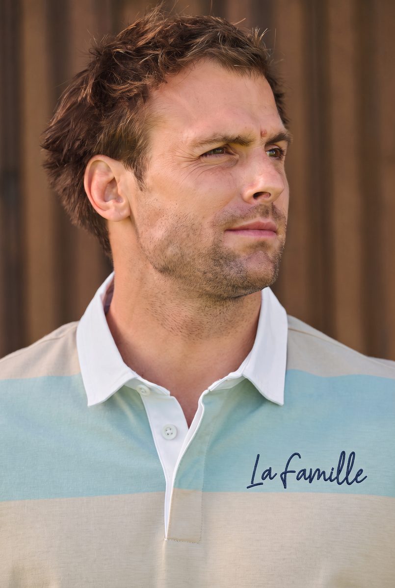 Polo rugby K285 rayé beige et menthe porté par un modèle, signature brodée La Famille côté cœur